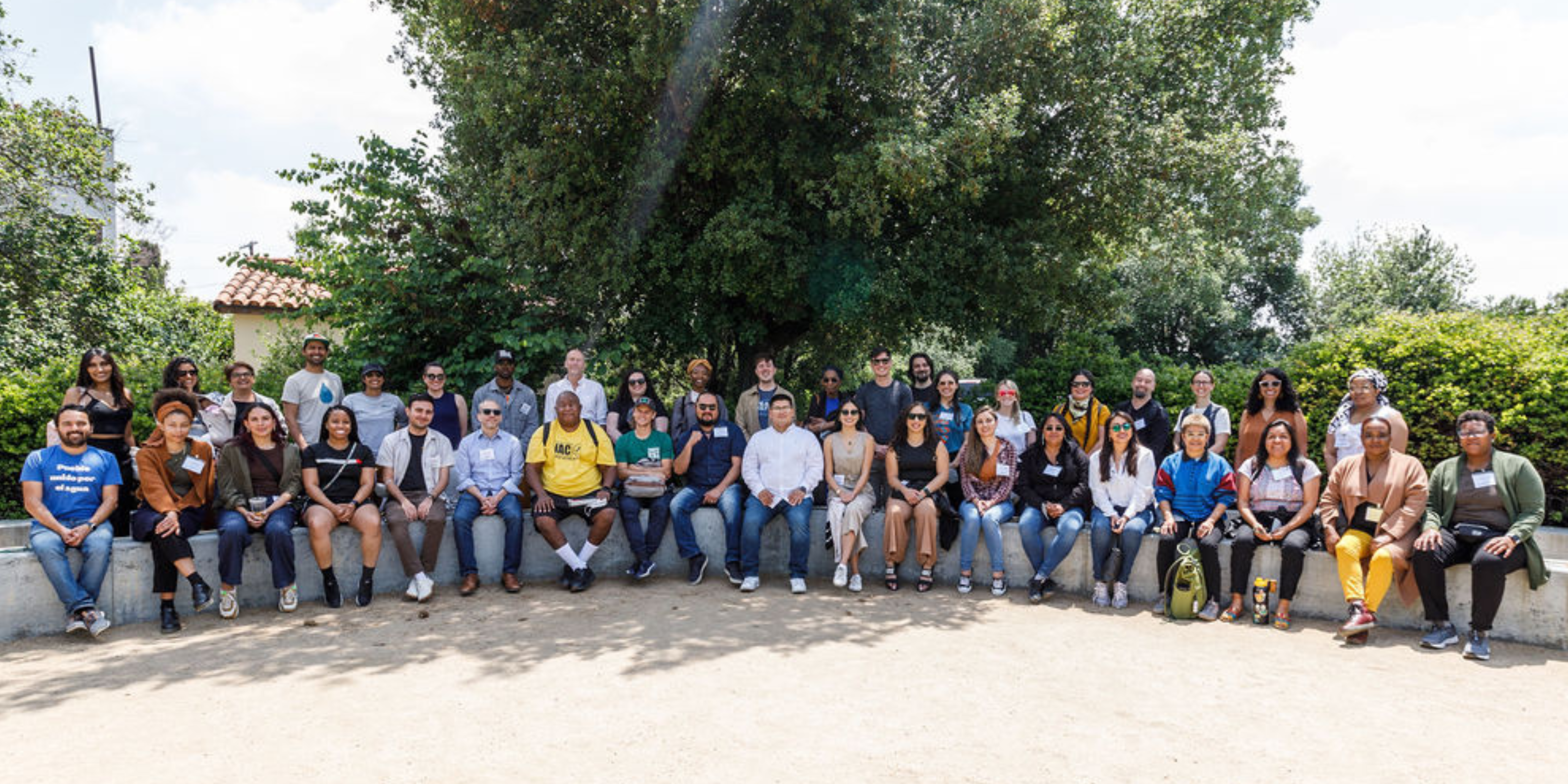 Group of 60 Water Equity and Climate Resilience Caucus members smiling and posing for a photo in front of trees.